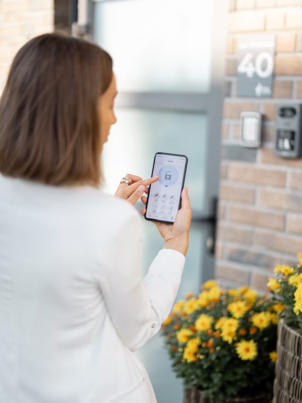 female-closes-the-door-or-turns-on-the-house-alarm-with-phone.jpg